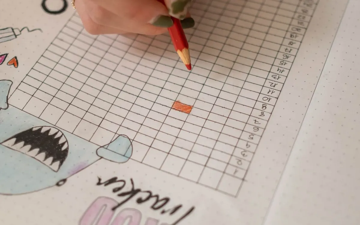Une main note son cycle dans un carnet avec un crayon rouge