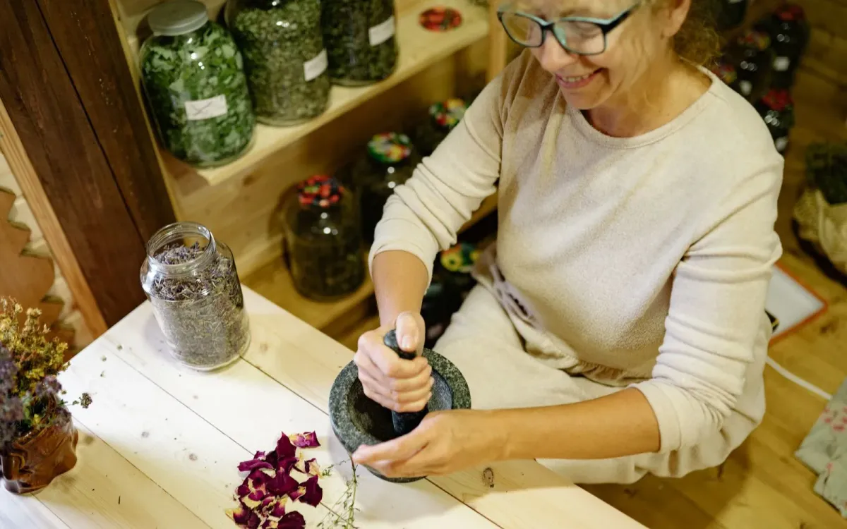 Femme préparant un mélange de plantes au mortier dans son atelier