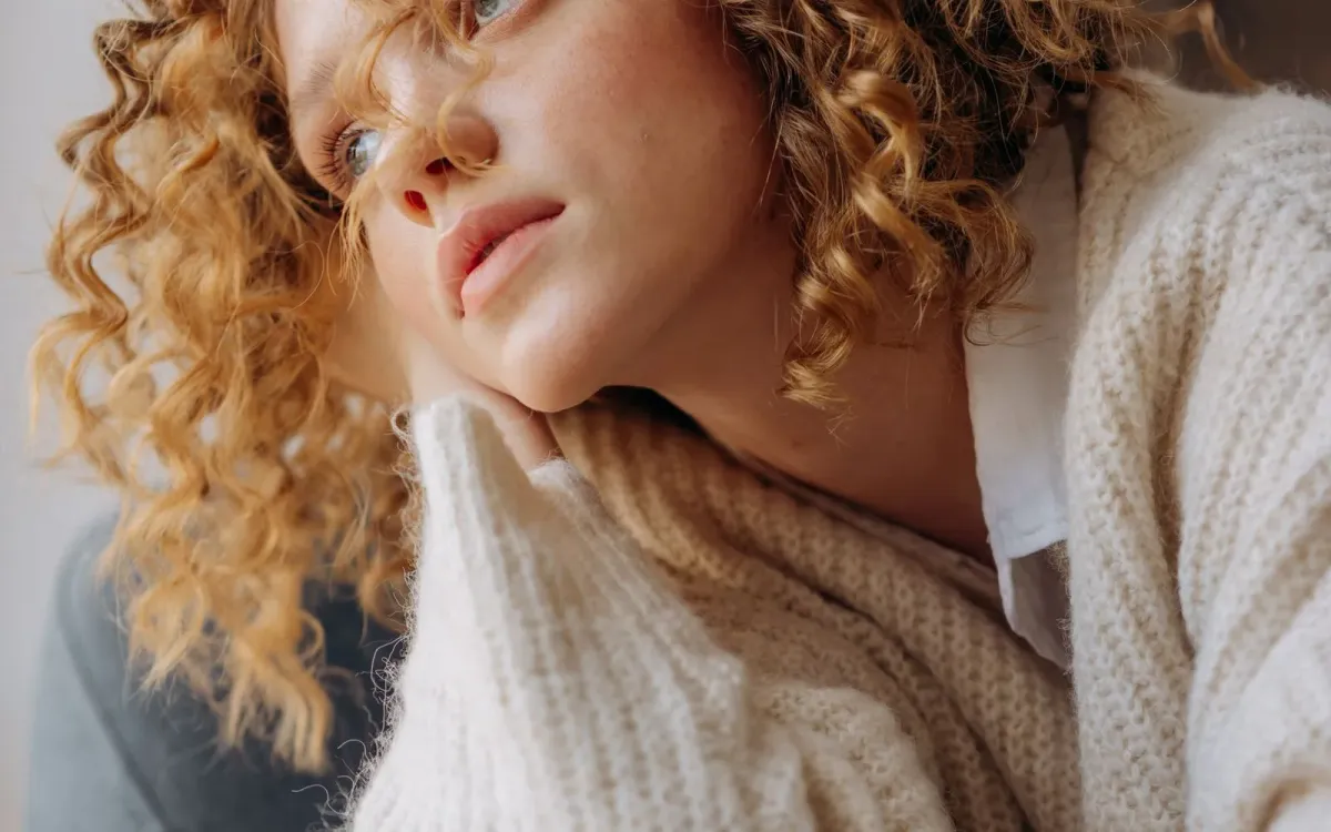 Une femme pensive enveloppée dans un pull tricoté